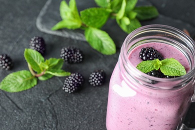 Photo of Delicious blackberry smoothie in mason jar on black table. Space for text