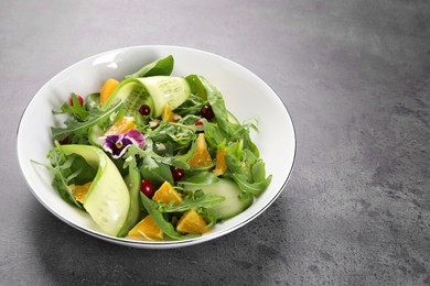 Photo of Delicious salad with cucumber and orange slices on gray table