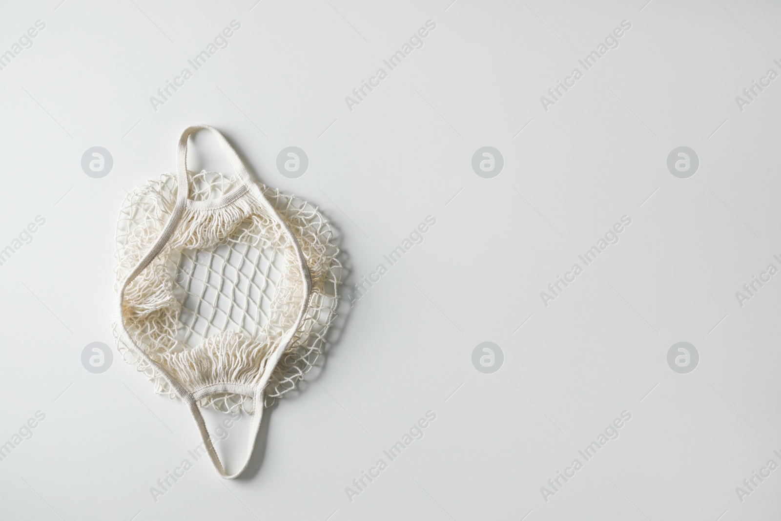 Photo of Empty net bag on white background, top view. Space for text