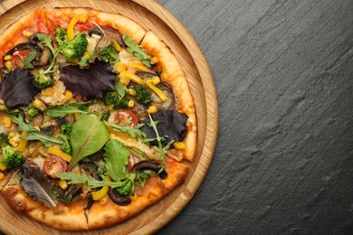 Photo of Delicious vegetarian pizza with mushrooms, vegetables and greens on black table, top view. Space for text