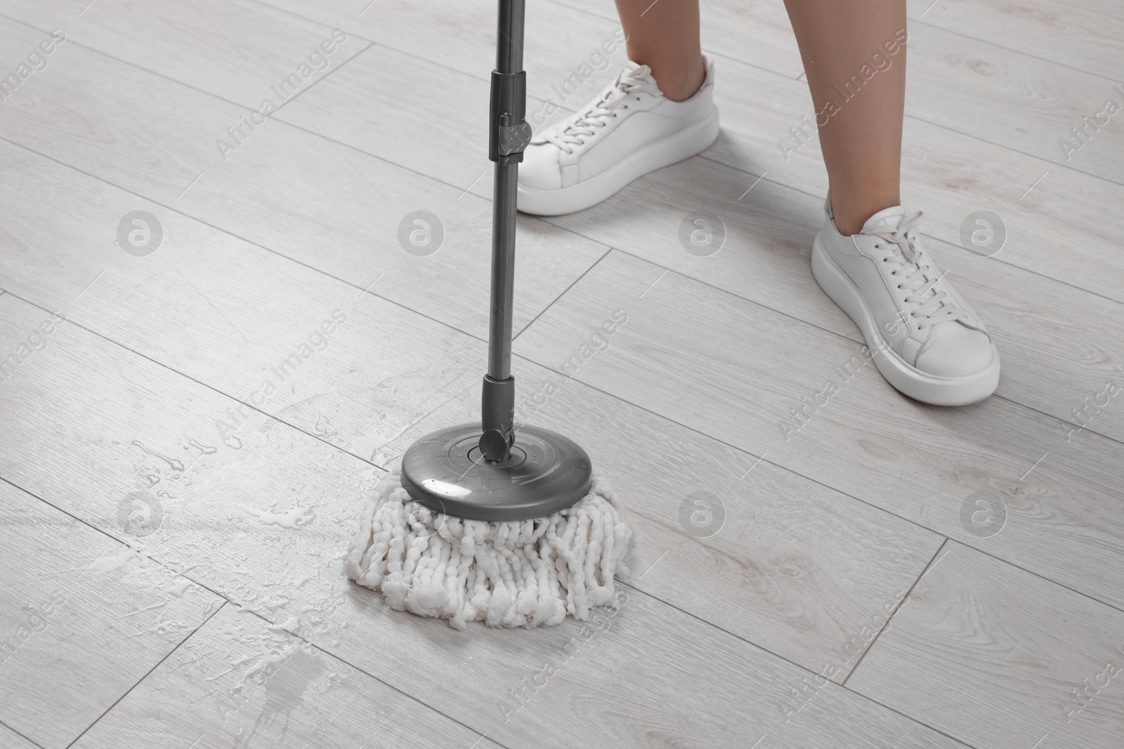 Photo of Woman cleaning floor with mop indoors, closeup