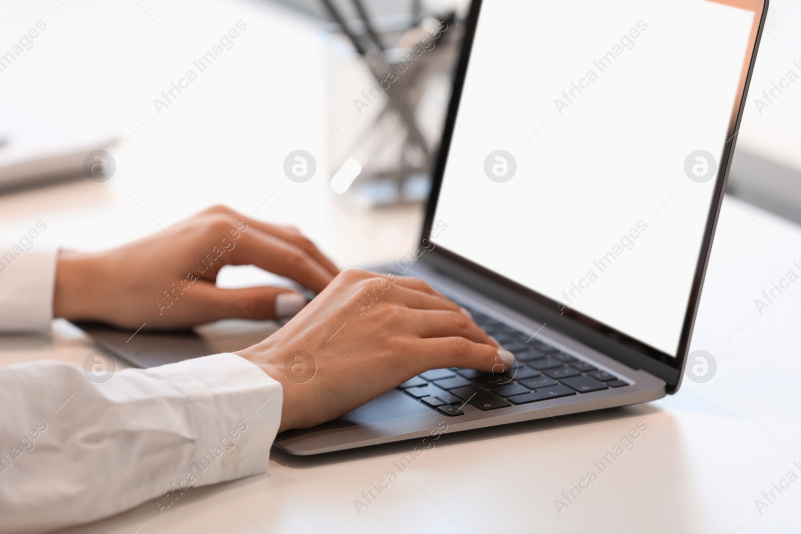 Photo of Woman using modern laptop at white desk, closeup
