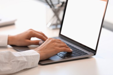 Woman using modern laptop at white desk, closeup