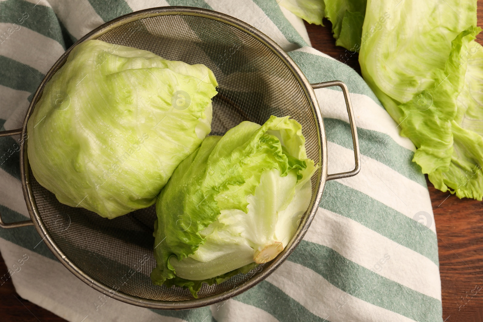 Photo of Fresh green clean iceberg lettuce heads and leaves on wooden table, flat lay