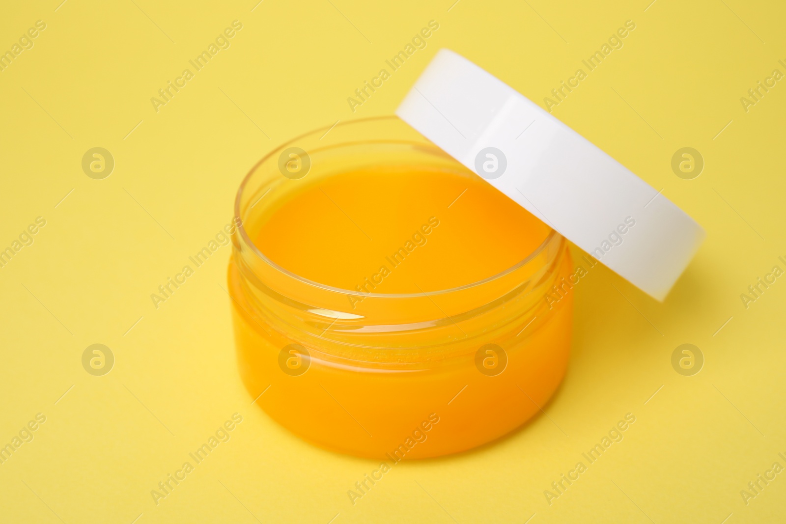 Photo of Open jar of petrolatum on yellow background