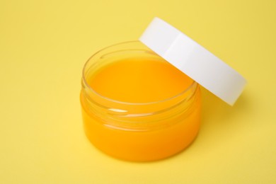 Open jar of petrolatum on yellow background