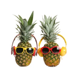 Photo of Funny pineapples with headphones and sunglasses on white background