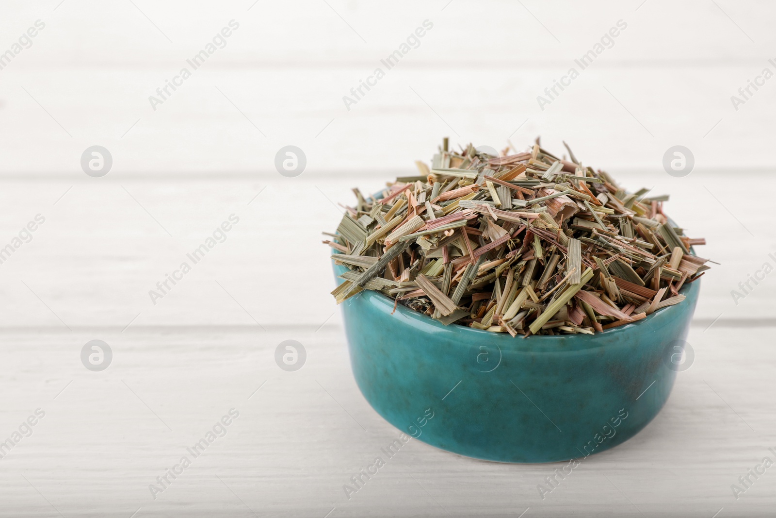 Photo of Bowl with aromatic dried lemongrass on white wooden table. Space for text