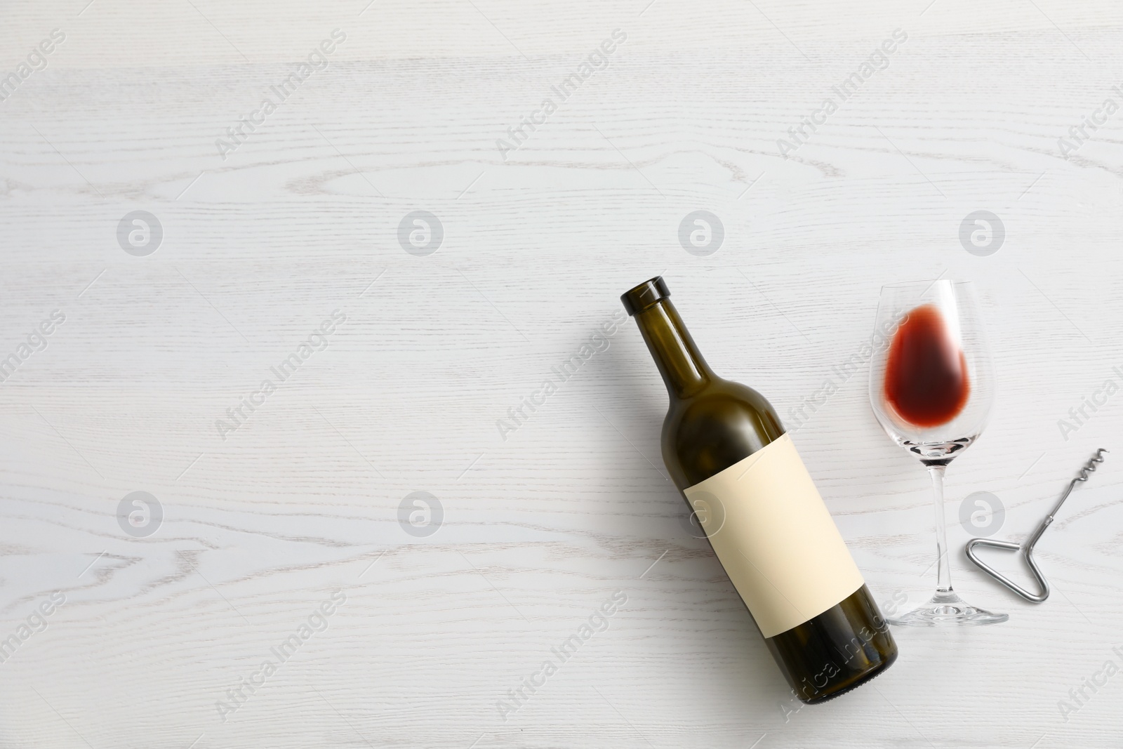 Photo of Flat lay composition with bottle of wine and elegant glass on white wooden background. Space for text