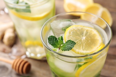 Photo of Glass of refreshing drink with lemon and mint on wooden table, closeup view. Space for text