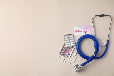 Photo of Flat lay composition with stethoscope and pills on beige background, space for text. Gynecology concept