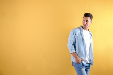 Young man in stylish jeans on color background with space for text