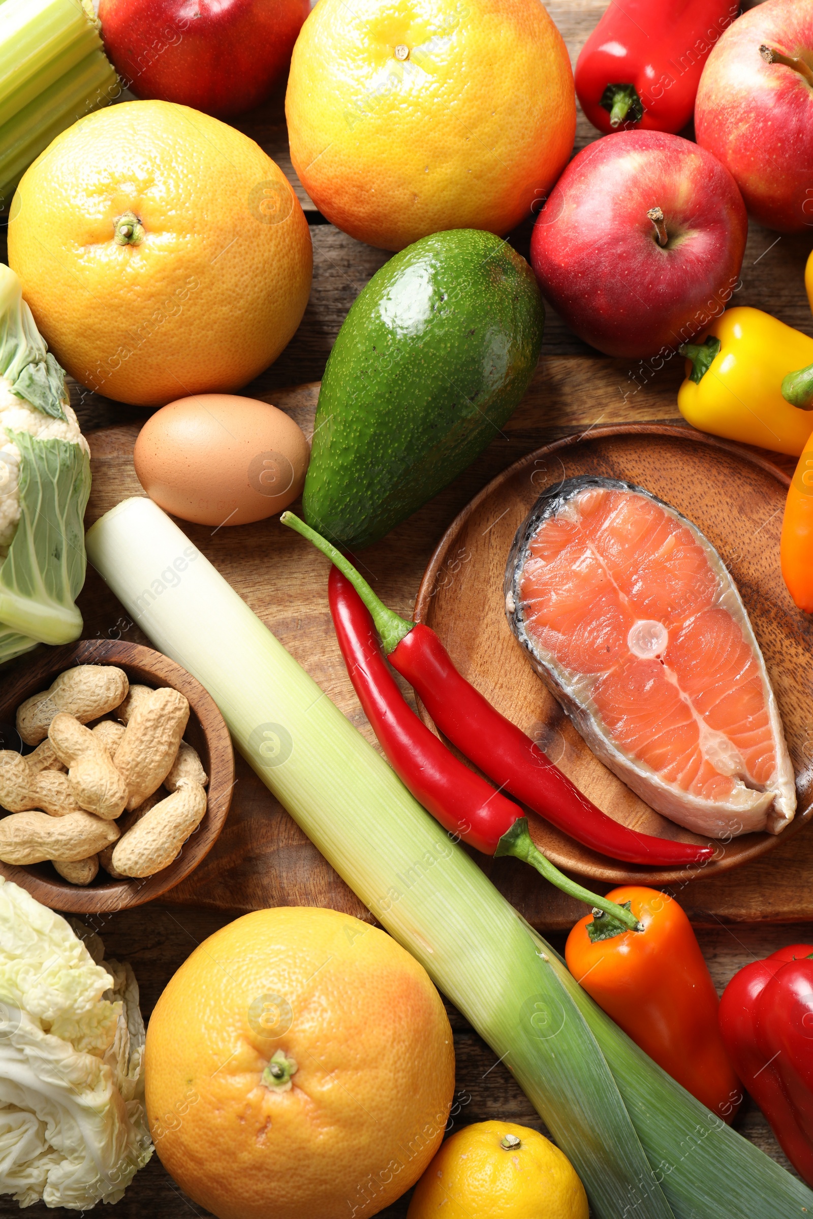 Photo of Healthy meal. Different vegetables and raw salmon on wooden table, flat lay