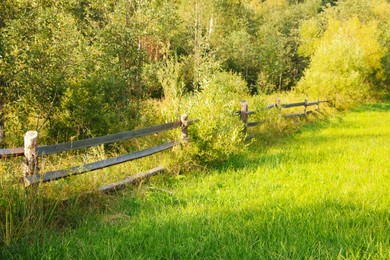 Photo of Beautiful view with wooden fence and bright green grass on sunny day