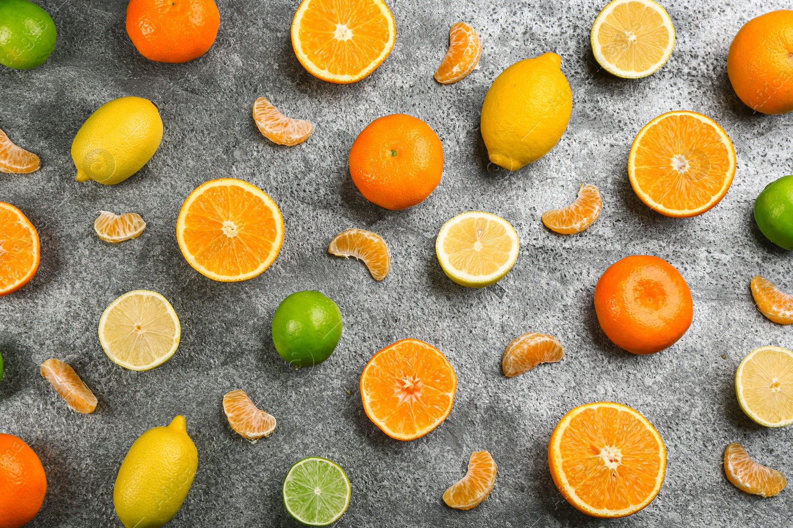 Photo of Flat lay composition with tangerines and different citrus fruits on grey background