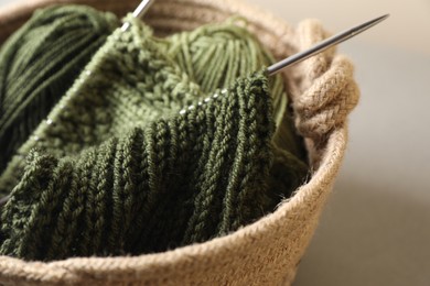 Photo of Green knitting, needles and soft yarns on light background, closeup