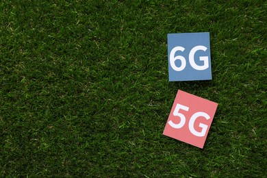 Photo of 6G and 5G technology, Internet concept. Cards on green grass, flat lay. Space for text