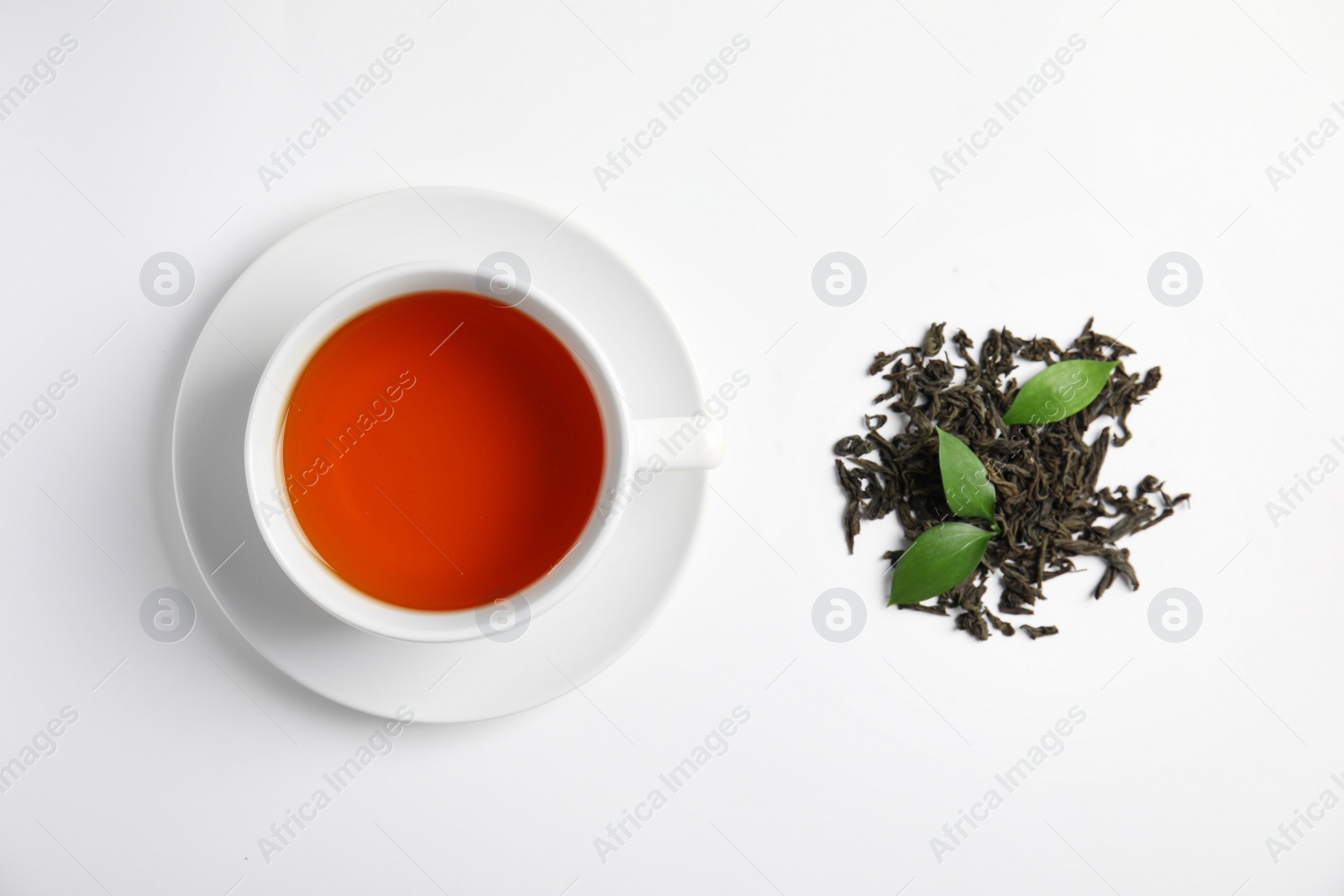 Photo of Cup of delicious tea with dried leaves on light background, top view