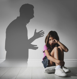 Image of Child abuse. Father yelling at his daughter. Shadow of man on wall