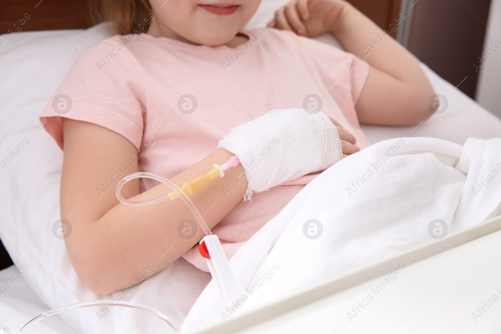 Photo of Little child with intravenous drip in hospital bed, closeup