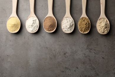 Photo of Spoons with different types of flour on grey background, top view. Space for text