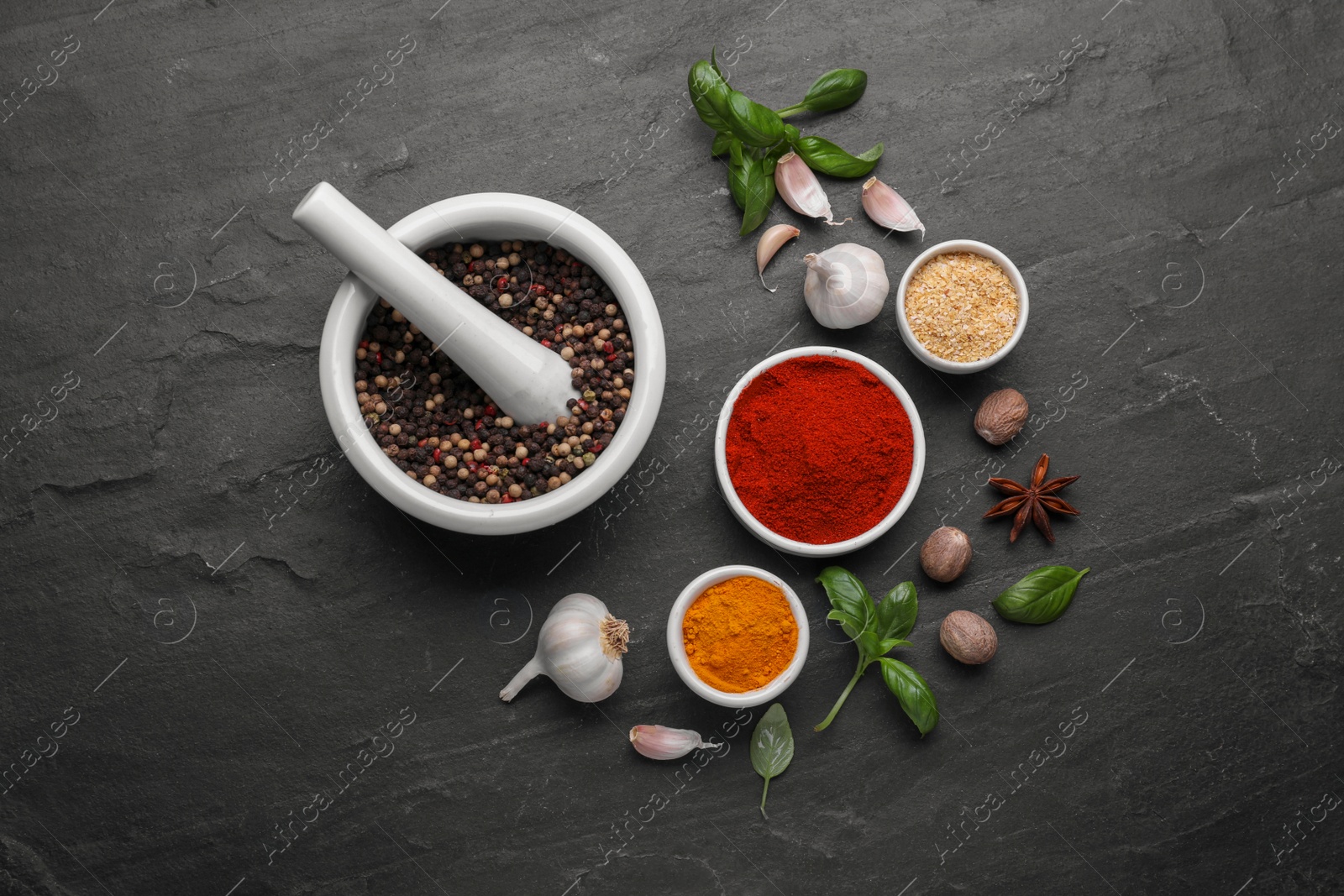 Photo of Mortar with pestle and different spices on black table, flat lay