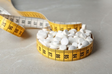 Photo of Weight loss pills with measuring tape on table