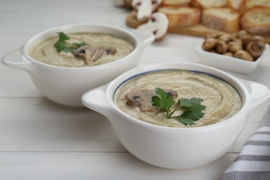 Photo of Delicious mushroom cream soup with parsley on white wooden table
