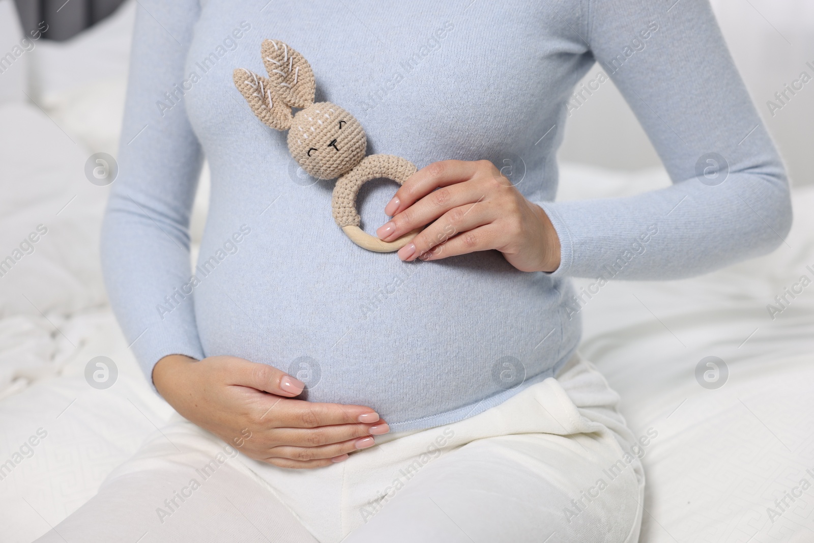 Photo of Pregnant woman with bunny toy on bed, closeup