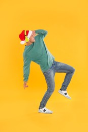 Emotional man with headphones on yellow background. Christmas music