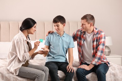 Photo of Parents talking with their teenage son about contraception in bedroom. Sex education concept