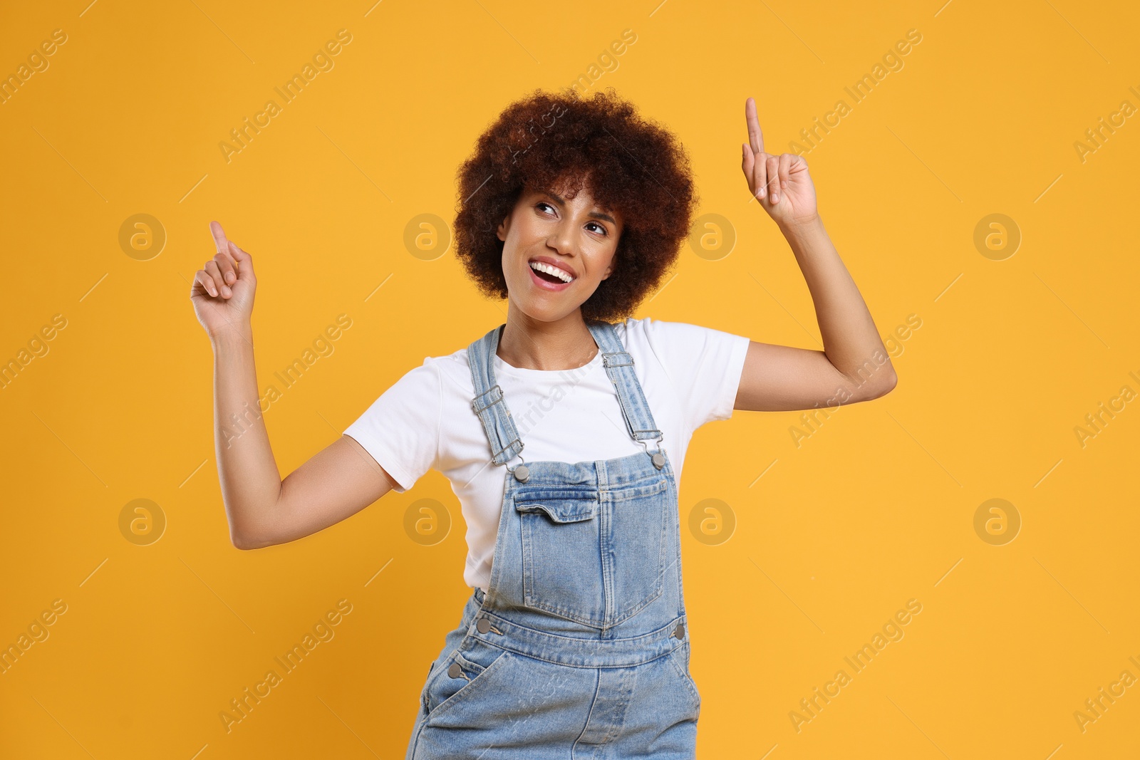 Photo of Happy young woman dancing on orange background