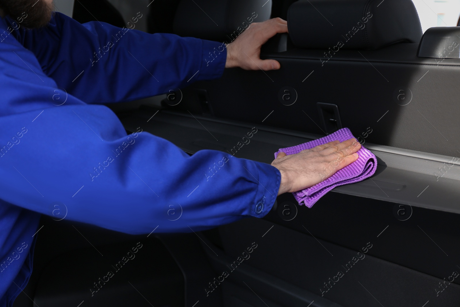 Photo of Worker wiping automobile trunk with rag at car wash, closeup