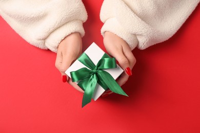 Christmas present. Woman with gift box on red background, top view