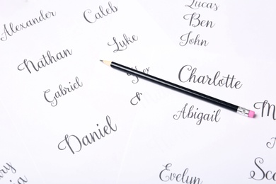 Photo of Ordinary pencil and different baby names written on paper, closeup
