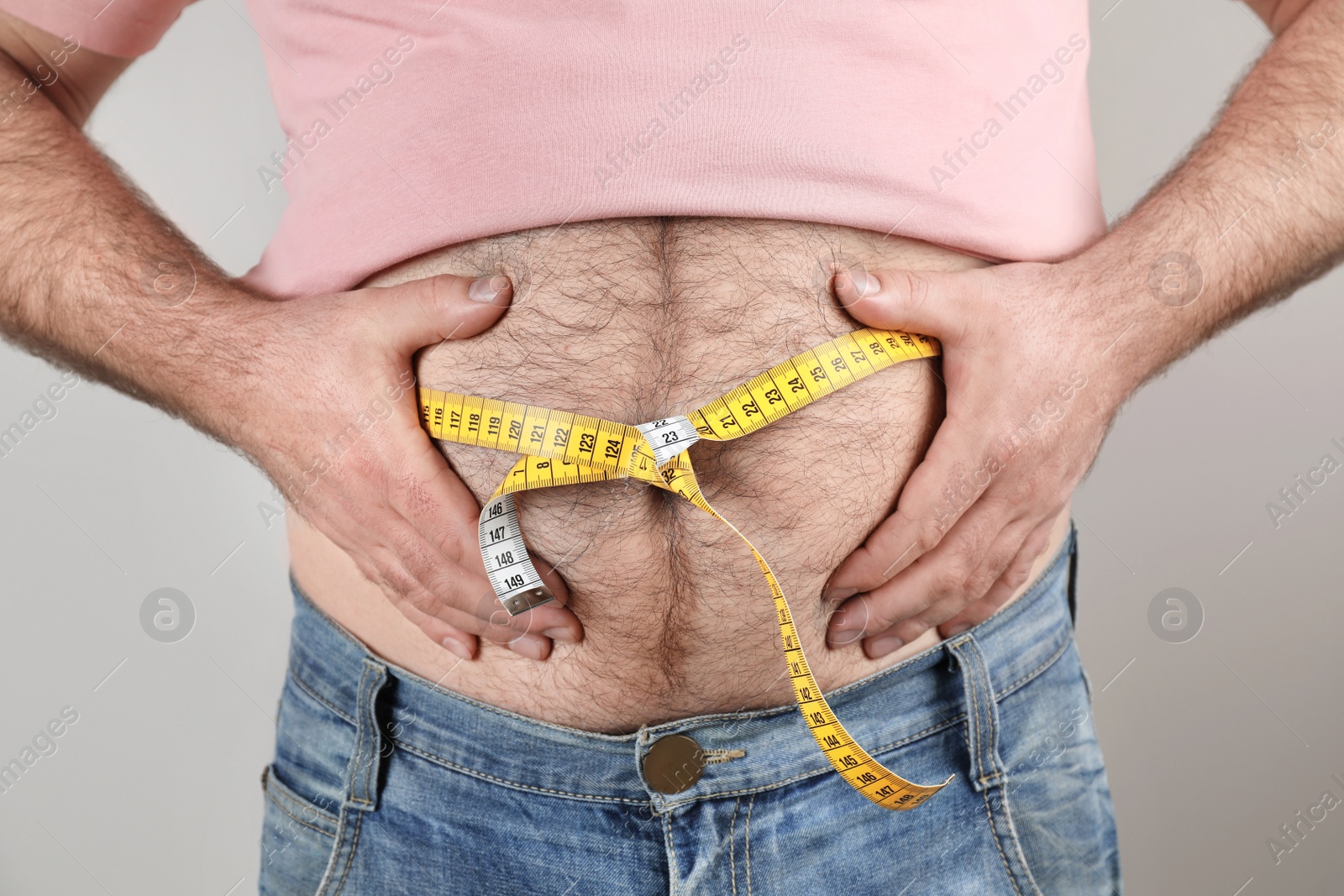 Photo of Overweight man with large belly and measuring tape on color background, closeup