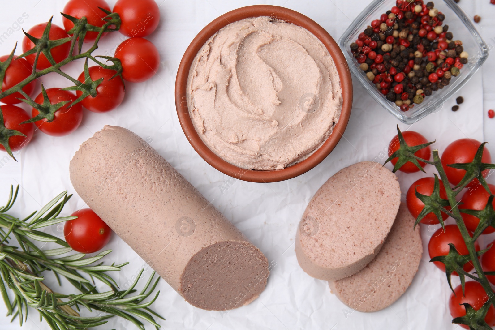 Photo of Delicious liver sausage, paste and other products on white tiled table, flat lay