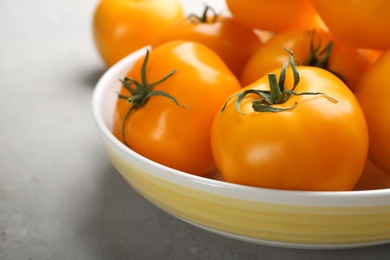Photo of Ripe yellow tomatoes on grey table, closeup