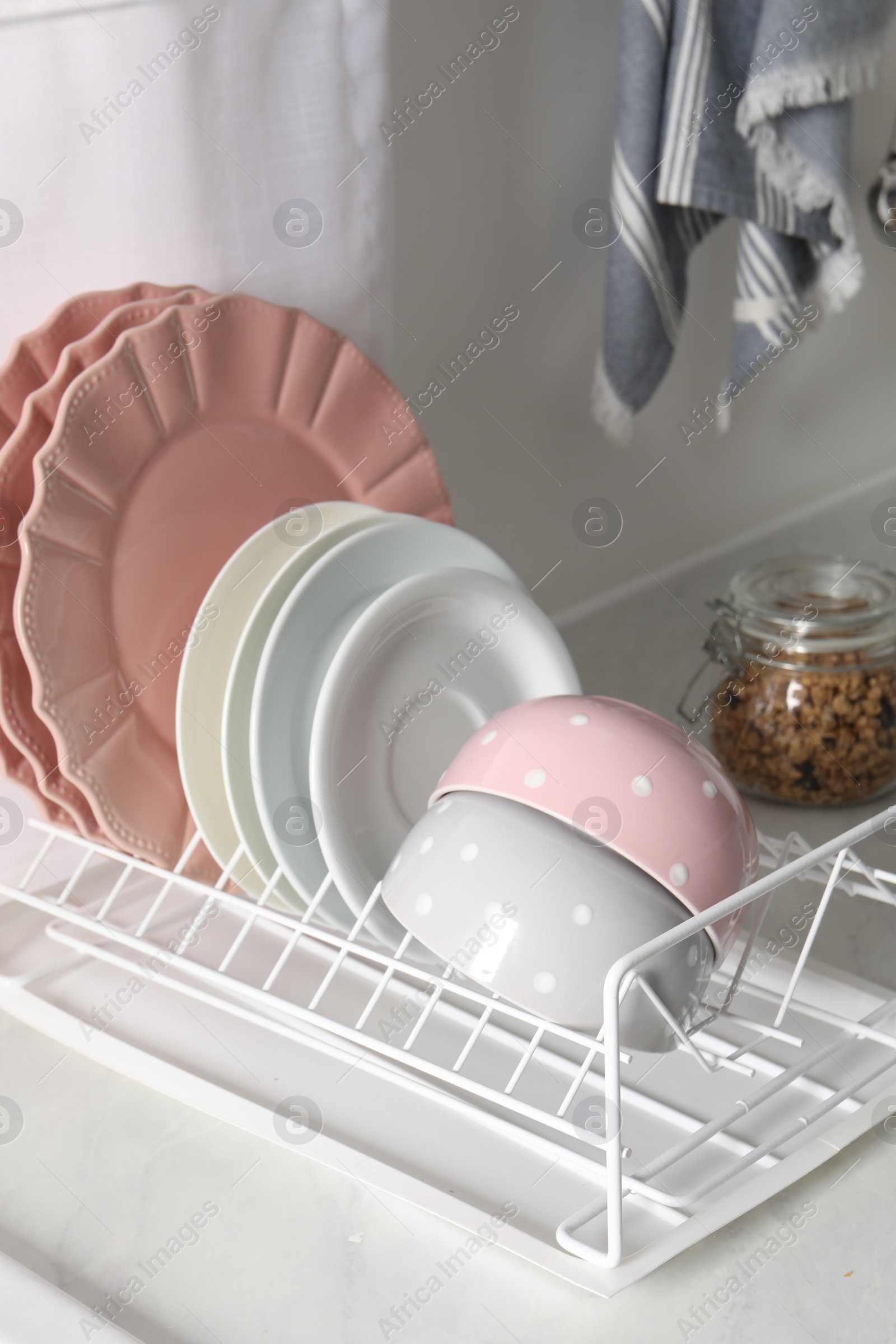 Photo of Drainer with different clean dishware on white table in kitchen