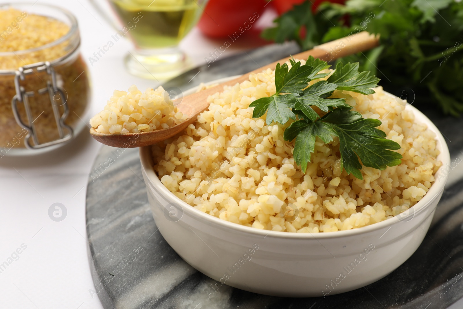 Photo of Delicious bulgur with parsley in bowl served on table, closeup