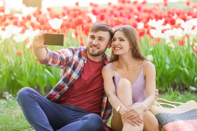 Photo of Happy young couple taking selfie in green park on sunny spring day