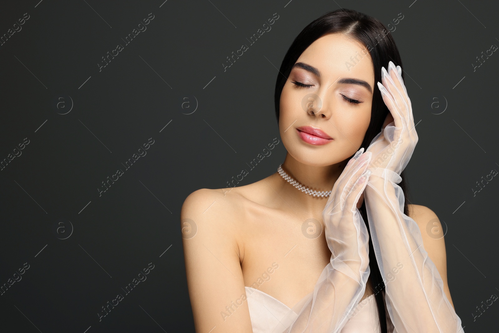 Photo of Portrait of young woman in long gloves on black background. Space for text