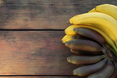 Photo of Different sorts of bananas on wooden table, top view. Space for text