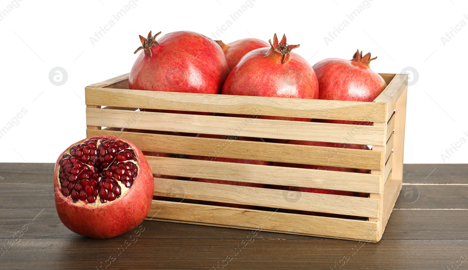 Photo of Fresh pomegranates in crate on wooden table against white background