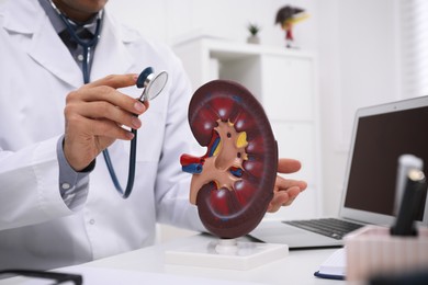 Photo of Doctor with stethoscope and liver model at workplace, closeup