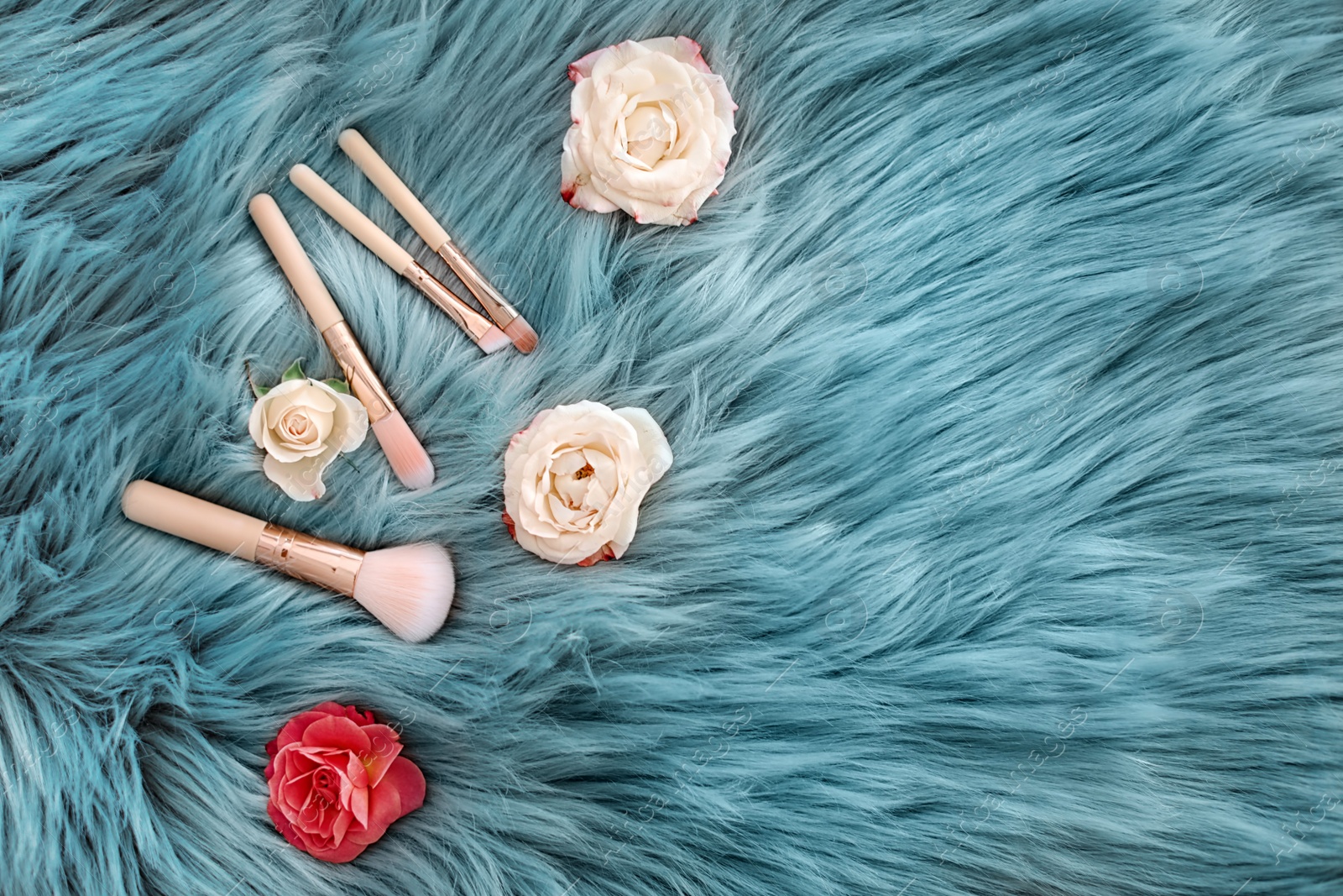 Photo of Flat lay composition with makeup brushes and roses on faux fur