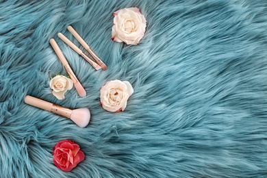 Photo of Flat lay composition with makeup brushes and roses on faux fur