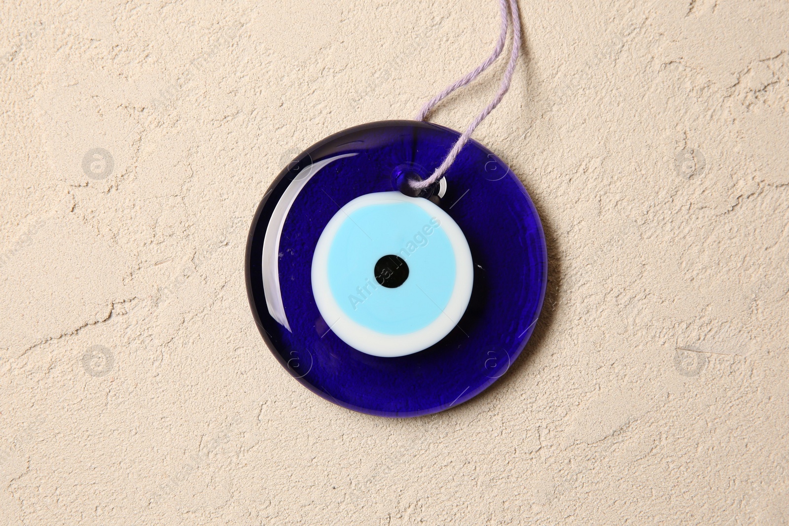 Photo of Evil eye amulet on beige textured table, top view