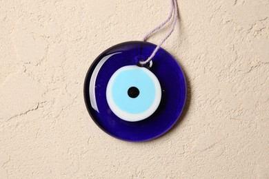 Photo of Evil eye amulet on beige textured table, top view