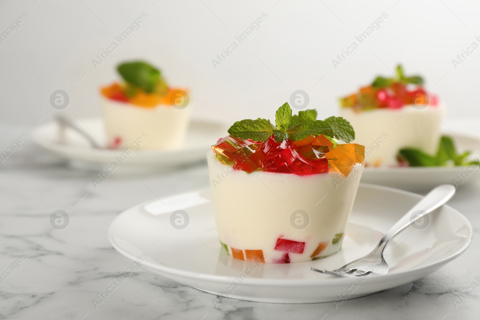 Photo of Delicious broken glass jelly dessert on white marble table, space for text